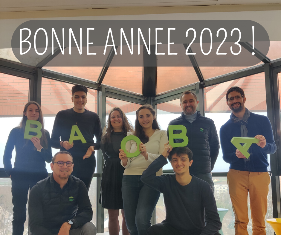 Une équipe souriante tenant des lettres vertes dans les mains. Ecriture disant bonne année 2023.